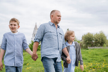 A father with his son and daughter on a walk.