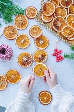 A child makes a garland of dried oranges for a holiday.
