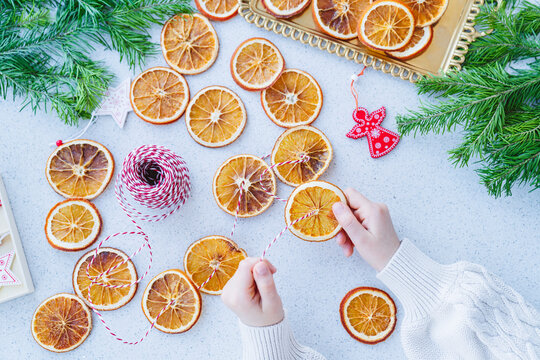 A child makes a garland of dried oranges for a holiday.