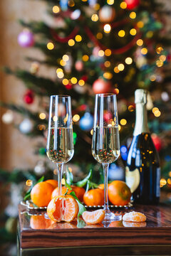 Champagne and tangerines in front of the Christmas tree.