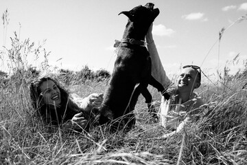 lesbian couple playing with their dog whilst out walking in a field