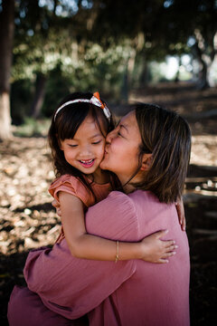 Mom Kissing Daughter at Sunset in Park in San Diego