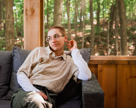 Attractive non-binary young person in their 20's sitting on deck.
