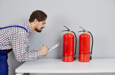 Man mechanic check fire extinguisher balloon in customer home. Male engineer or technician test...