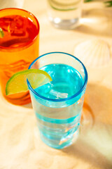 Summer non alcoholic cocktails in colorful glasses on beach with white sand. Summer sea ocean vacation and travel concept. Beach party.
