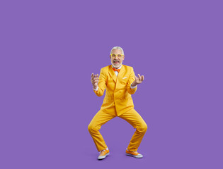 Excited aged man in eccentric suit isolated on purple studio background celebrate win or victory....