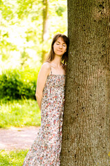 A young pretty girl in a long dress dreamily embraces a tree with her eyes closed.Ecology.Dreams. Financial growth. Reliability. Success. Investment