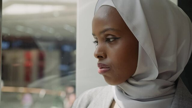 African-American woman adjusts hijab in shopping mall