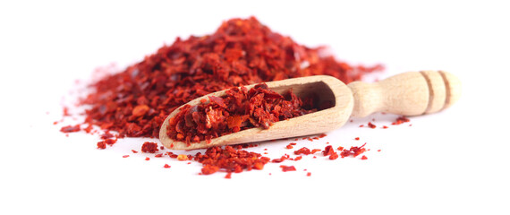 Heap of dried red chili flakes and wooden spoon isolated on white background. Spices and herbs.	
