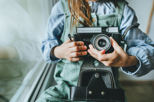 Unrecognizable little girl taking photo by film camera