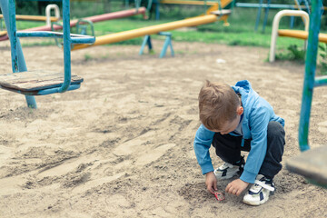 Fototapeta na wymiar A little boy plays in the sand on the playground