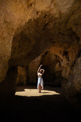 Happy woman in sunlit grotto in summer