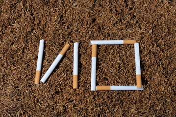 NO cigarettes lettering. Against a background of dry smoking tobacco. Broken cigarette. World No Tobacco Day, May 31