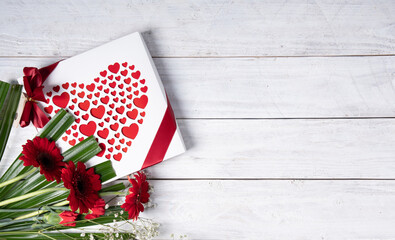 Valentine's day gift, red heart praline box and flower bouquet on white table