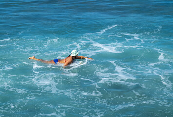 Obraz na płótnie Canvas Person wearing a sun hat swimming in the ocean.