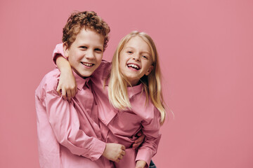 cute joyful children stand hugging each other in pink clothes on a pink background. Themes of relationships and friendship between children