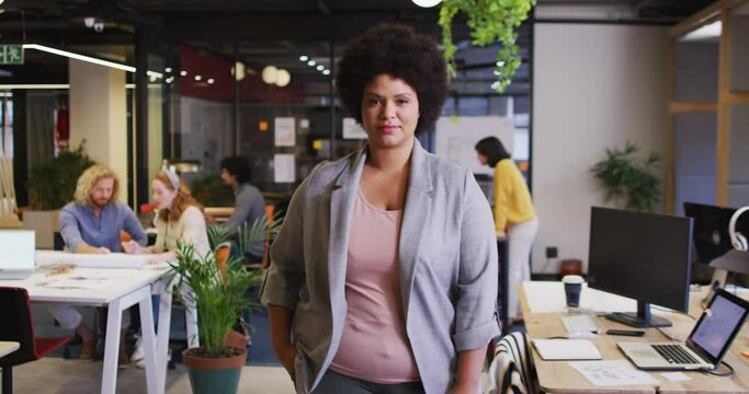 Portrait of happy biracial businesswoman looking at camera at office