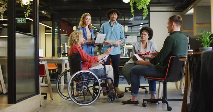 Happy disabled and diverse business people discussing work at office
