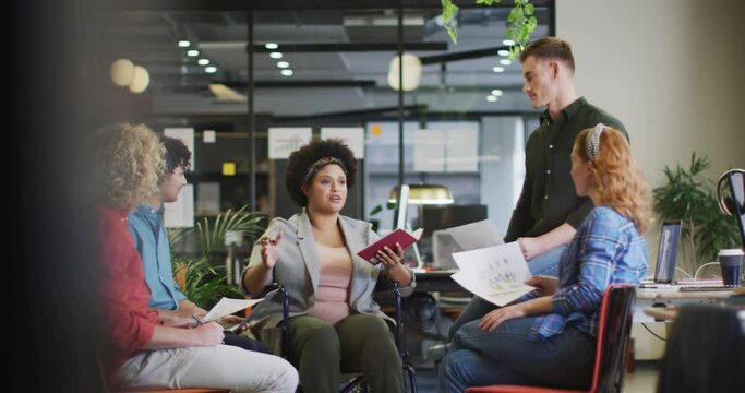 Happy disabled and diverse business people discussing work at office