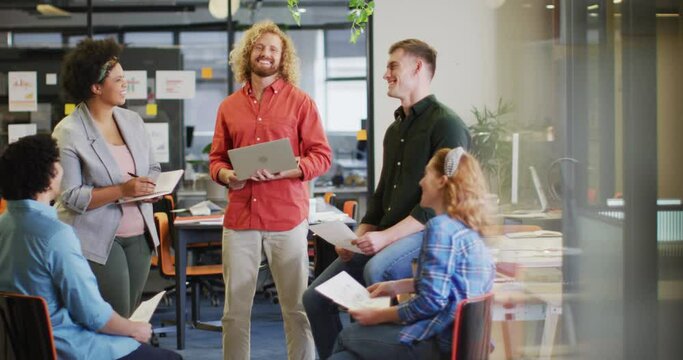 Happy diverse business people discussing work with documents at office