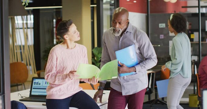 Happy diverse business people holding documents and discussing work at office