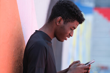 Portrait of young man with curly hair looking at smartphone smiling