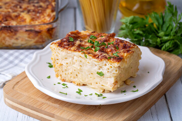 Pasta casserole bechamel sauce topped with melted mozzarella cheese and served in a white baking dish on a table (Turkish name; firinda makarna or firin makarna)