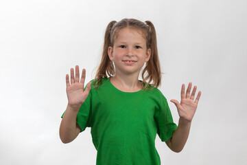 Smiling little girl holding up her hands in green t-shirt over white background