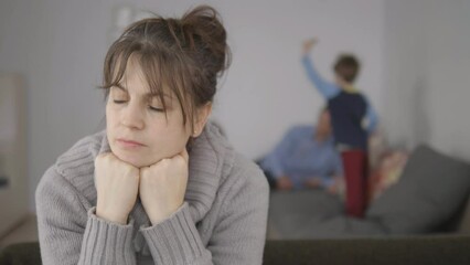 Depressed mother foreground portrait focus, blurred family in background