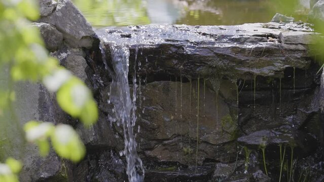 Close up View of water streaming down a rock in garden. Deer Lake Park. Taken in Burnaby, Vancouver, British Columbia, Canada. Nature Background. Slow Motion