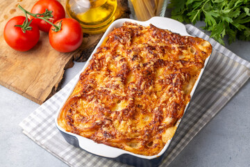 Pasta casserole bechamel sauce topped with melted mozzarella cheese and served in a white baking dish on a table (Turkish name; firinda makarna or firin makarna)