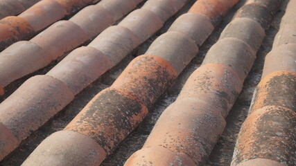 Rustic house roof. Old tiles. Weathered white wall texture. 