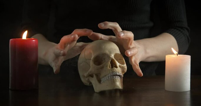 Conjure with a skull. Tense hands with a human skull.