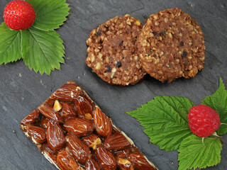 top view of almond bar and granola cookies with fruits, strawberry and raspberry with leaf, healthy high protein snack with nuts for sports nutrition