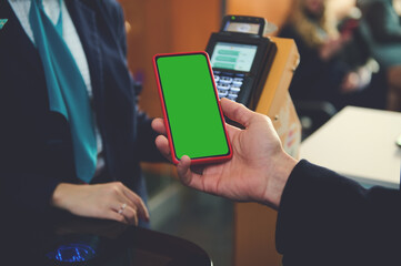 Smartphone. Green chroma key blank screen with copy ad space for mobile apps in a hand, near bank terminal while going through flight check-in board