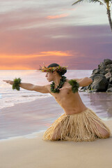 Male Hula Dancer on the beach with a sunset sky of fire in the background  - obrazy, fototapety, plakaty