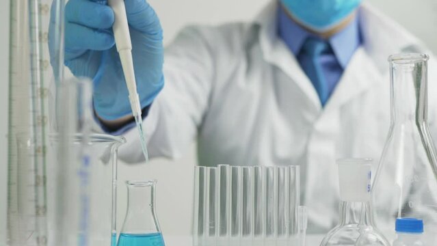 Scientific researcher dosing solution with pipette for study in the laboratory