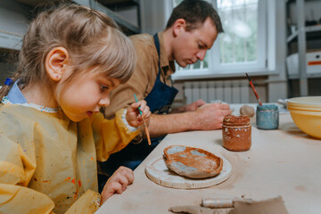 Father and his daughter at a master class in clay modeling