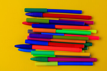 Multi-colored markers with mixed caps. Creative concept. Yellow background with selective focus and...