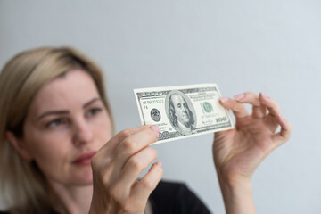 Woman holding dollar bill and looking at it with watermarks closeup.