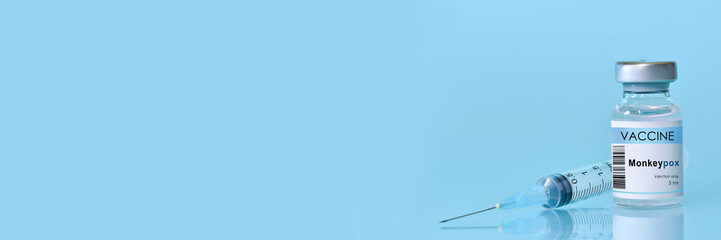 Vaccine Monkeypox and Smallpox vial with a syringe on a blue background.The concept of medicine,...