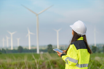 women engineer working and holding the report at wind turbine farm Power Generator Station on...