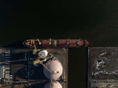 A direct overhead aerial view of a raw goods agriculture cargo ship at a dock in Hamilton, Ontario's industrial port.