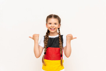 A little girl with a German flag on a T-shirt, with long hair in pigtails, points up with her index finger sideways at your advertisement on a white isolated background. Language courses.