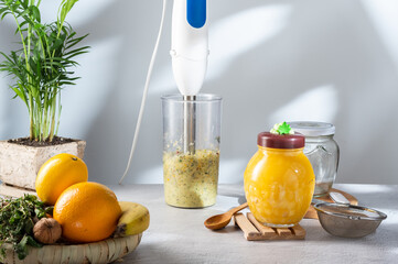 Prepare with a blender. Mix food with a blender. Fruit puree and honey. Shadow and light from the window.