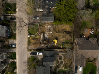 An aerial view above a home in a neighbourhood being torn down, demolished by an excavator during...