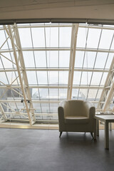 A white armchair with a coffee table on the background of the window. Space for copying an empty window template. Classic upholstered armchair by the window in the room. High quality photo