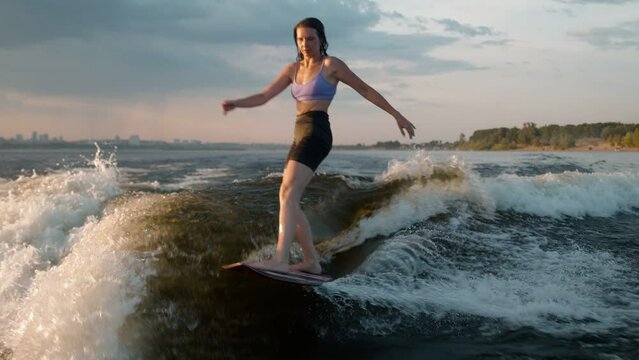 A female surfer jumping on a wakeboard. An experienced wakeboarder splashes water drops into the camera.