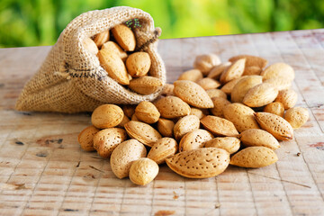 Almonds. pile of almonds in sack, on wooden table. Selective focus