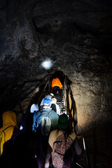 Tourists explore an underground cave, a group of people stuck deep underground, a karst mine, a staircase in a cave at the bottom of a well, a speleo expedition.